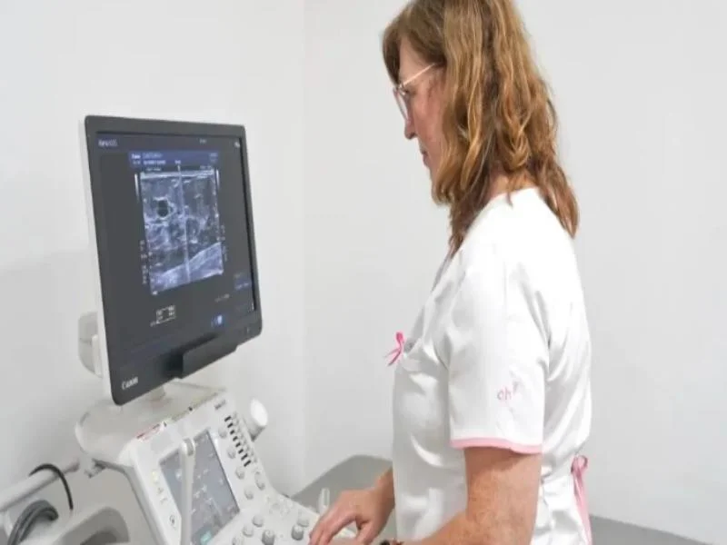 Profesional de salud junto a un equipo de diagnóstico por imágenes durante un estudio mamario.