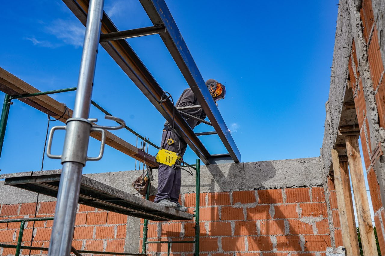 Trabajador instala una estructura metálica durante las obras de ampliación de un establecimiento educativo de Lanús.